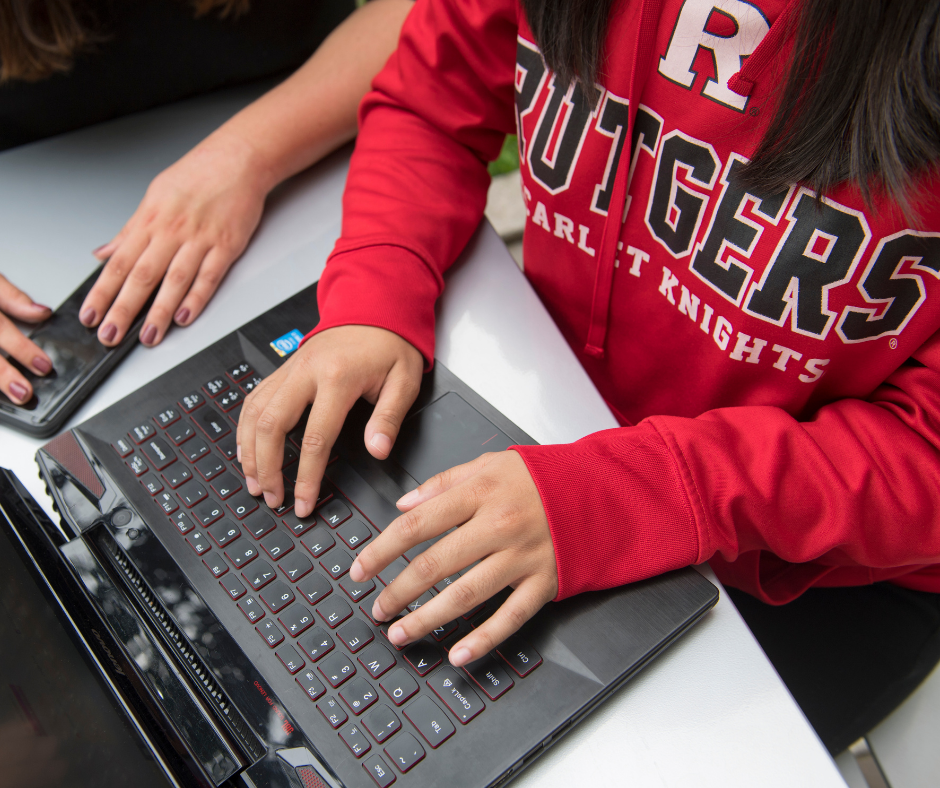 Image of a person in a Rutgers sweatshirt working on a laptop
